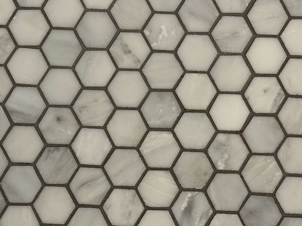 Close-up of hexagon marble tiles with darkened grout lines, indicating the need for professional tile and grout cleaning in San Pedro, CA.