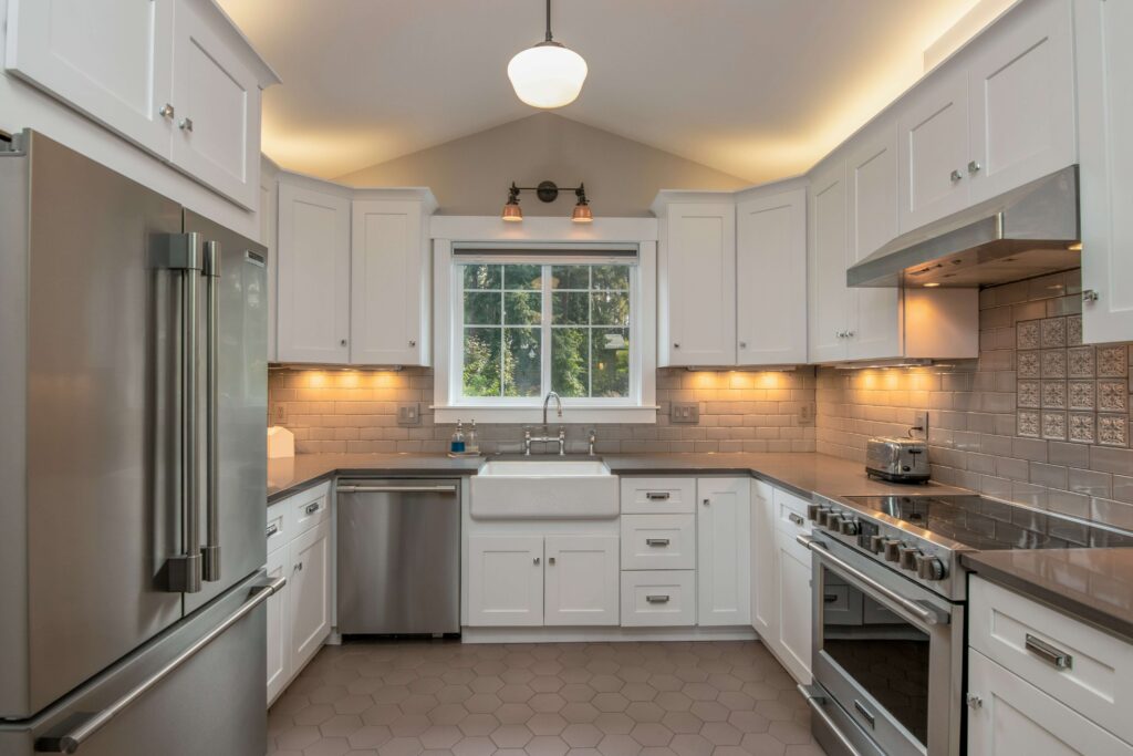 Modern kitchen with stainless steel appliances, subway tile backsplash, and hexagonal floor tiles in a Manhattan Beach home.