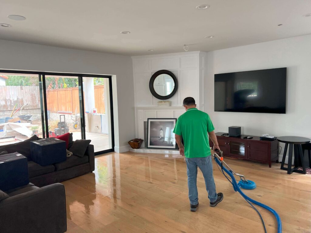 Water damage technician using extraction equipment on wet hardwood floor inside a San Pedro hillside home